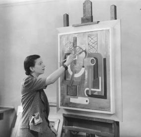Irene Rice Pereira with her painting "Curves and Angles Composition" (1937), 1938